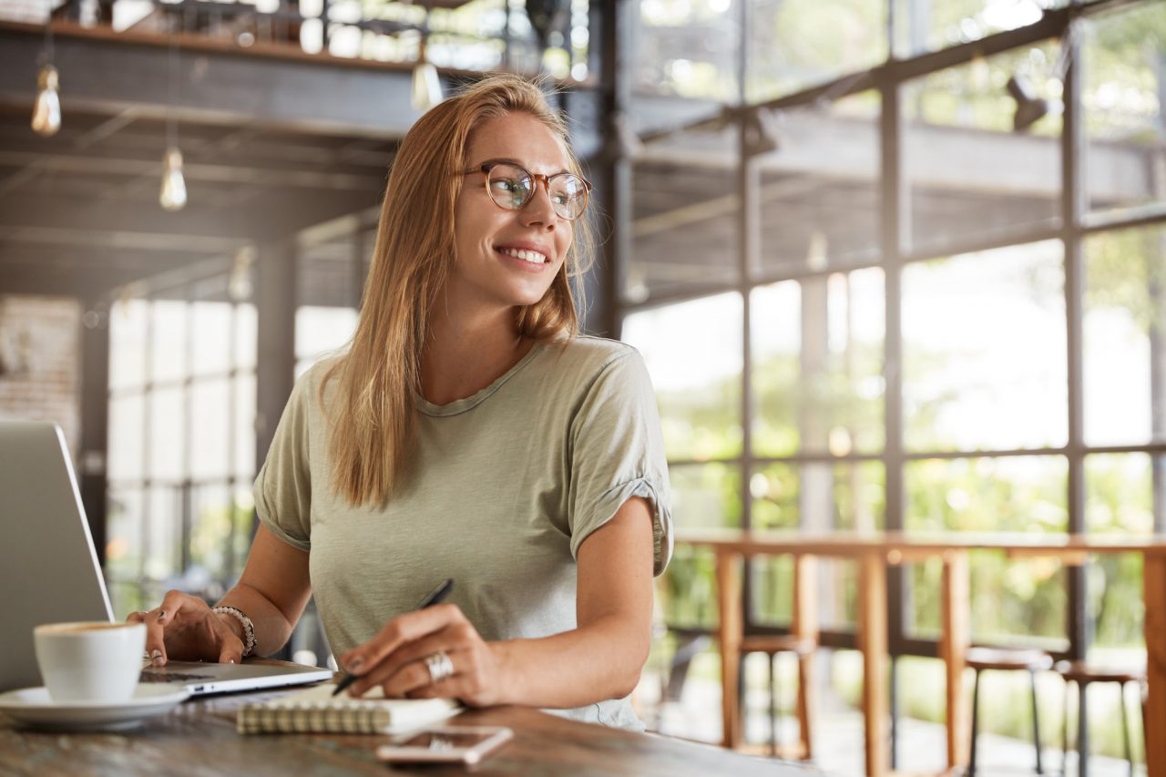 happy-female-copywriter-writes-ideas-in-notepad-and-searches-inforamtion-on-laptop-computer-spends.jpg