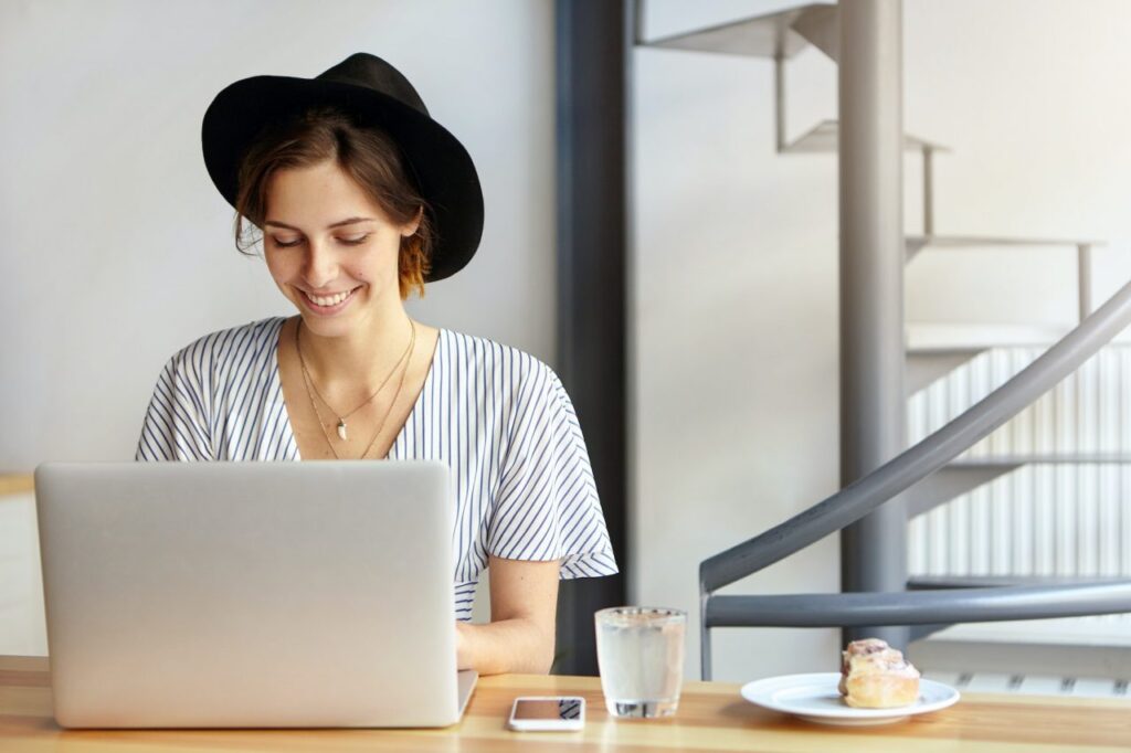 pretty-young-female-copywriter-wearing-black-hat-and-stripped-blouse-working-on-laptop-computer-loo.jpg